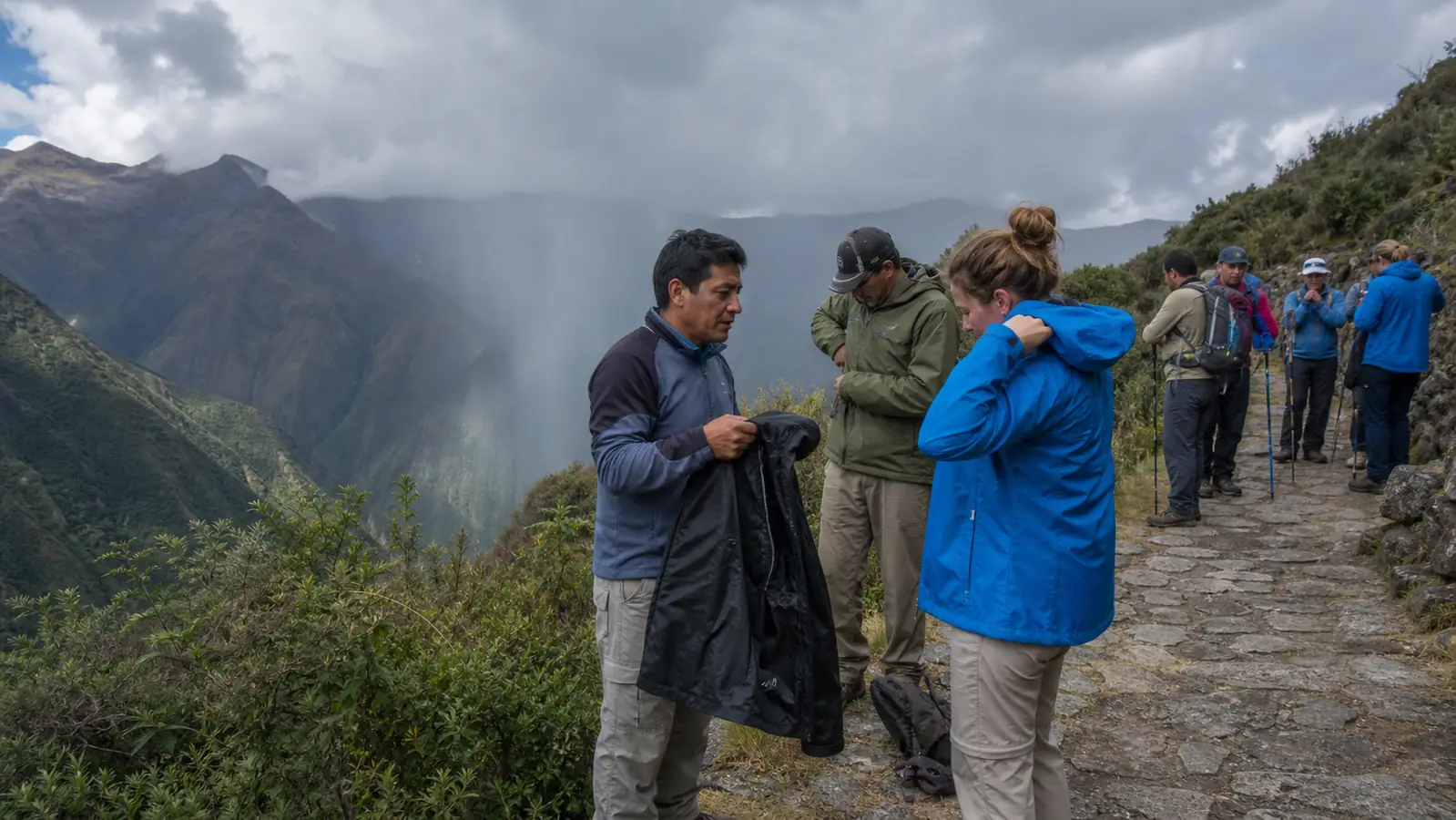 Hikers putting on waterproof layers as October rain crosses an Andean valley
