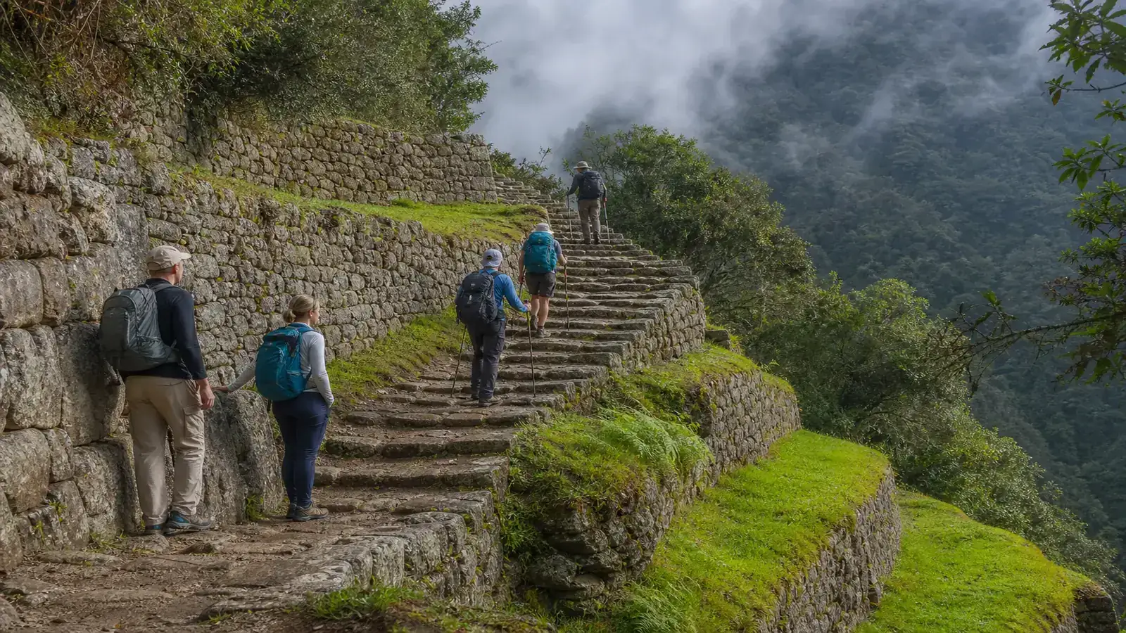 Light-pack hikers and multi-day trekkers climbing an Inca stone staircase